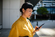 © Davor - Businesswoman using smartphone outside office building