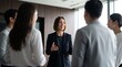 © Eve - Smiling businesswoman leading team discussion with colleagues in modern office, driving marketing strategy, corporate leadership coaching, business training presentation, and project management