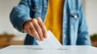 © Zarana  - A person in a denim jacket casts a ballot into a voting box during an election. Civic duty and democracy concept for political campaigns.
