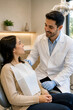 © Hoseein - Friendly male dentist examining a smiling female patient in a modern dental