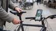 © Tonton1541 - AI Travel Planning Mobile App concept. Man adjusting bicycle seat with navigation app on phone mounted on handlebars