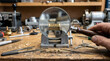 © Digion - A skilled locksmith technician uses a magnifying glass to inspect a brass lock cylinder mechanism secured firmly in a metal bench vise for careful repair work at a traditional mechanical workshop