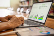 © Vahn - closeup of businessman typing on laptop with a digital tablet and stylus pen lying on a wooden desk in a library background.