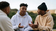 © CinimaticWorks - group of four men sitting outdoors having conversation, male friendship and community support concept