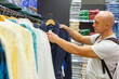 © Екатерина Переславце - Bald caucasian man reads the care label and washing instructions on a navy terry bathrobe, useful for retail, product quality and consumer choice content.
