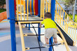 © leungchopan - Toddler boy climbing up rope net structure at outdoor playground