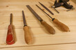© Semiglass - Set of vintage woodworking chisels with brass ferrules and worn blades rests on light wooden workbench