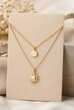 © Richafuji - Elegant Layered Thin Gold Necklaces with Sun and Disc Pendants Displayed on White Card with Neutral Background