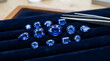 © Ceo - Assorted loose blue sapphires on dark fabric.