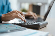 © Garun Studios - Two colleagues use a calculator and laptop for finance planning, combining budgeting, accounting, expense and cost analysis in a report that helps their business compare revenue and finance goals.