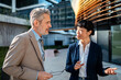 © Davor - Two business colleagues discussing strategy outside modern office building