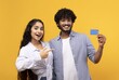 © Prostock-studio - Excited South Asian Young Couple Smiling And Holding Credit Card While Posing Together At Studio With Yellow Background. They Are Demonstrating Financial Success And Confidence In Business Concept.