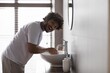 © Prostock-studio - Smiling Young Man In His Twenties, Washing Hands With Soap At A Modern Bathroom Sink, Promoting Good Hygiene Practices In Home Setting. Personal Care And Cleanliness Concept.