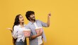 © Prostock-studio - Smiling Young Couple, Asian Male And Female, Happily Holding Popcorn Buckets While Enjoying Movie Together In Studio With Yellow Background, Expressing Joy And Excitement. Entertainment Concept.