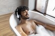 © Prostock-studio - Smiling Male Adult Relaxing In Bathtub Full Of Bubbles, Listening To Music With Headphones In Modern Bathroom. Peaceful Atmosphere Reflects Spa And Wellness Concept.