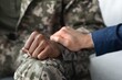 © Prostock-studio - Caring Gesture. Supportive Man Holding Hand Of African American Soldier In Uniform, Sharing An Emotional Moment Together In Hospital Setting, Focused On Mental Health Support. Healthcare Concept.