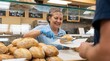 © Eduardo - Friendly bakery worker serving fresh bread to a customer in a grocery store