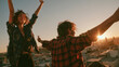© pattozher - Joyful Sunset Celebration: Two friends exult at sunset, arms raised in a jubilant embrace, silhouetted against the warm, golden hues of the fading day, embodying freedom and pure happiness.