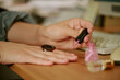 © AnnaStills - Hands of Caucasian female employee applying pink nail polish at retro office desk, slacking off during work hours. Close up shot illustrating workplace distraction and procrastination