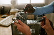 © AnnaStills - Hands of African American man and Caucasian woman repairing computer hardware in retro office. Close up shot suitable for tech support, vintage technology, and teamwork concepts
