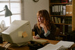 © AnnaStills - Young adult Caucasian woman working on retro computer in vintage office, looking focused. Image represents nostalgia and technology evolution, ideal for corporate history campaigns