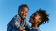 © Alex Photography - A joyful mother lovingly holds her smiling child against a clear blue sky, capturing a moment of happiness.