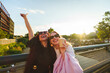 © pablo - Two friends laughing, having fun outdoors with takeaway coffee at golden hour
