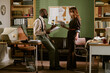© AnnaStills - Diverse young adult colleagues discussing paperwork in retro office setting. Image represents corporate history, vintage business communication, and legacy workflow systems, wide shot