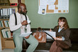 © AnnaStills - Diverse young adult colleagues discussing documents in retro office setting. Image represents vintage corporate communication and is suitable for business history articles
