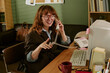 © AnnaStills - Young adult Caucasian woman working in retro office, talking on vintage telephone and smiling. Image suitable for nostalgic corporate communication and vintage business marketing