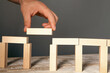 © Artvibe - Conceptual image of risk, chance and success. Businessman's hand placing wooden blocks on the top of a domino effect.