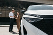 © wedmoments.stock - Professional car dealer talking with a businesswoman next to a new modern vehicle. Concept automotive sales, business mobility and car selection.