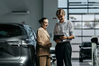 © wedmoments.stock - Salesperson showing vehicle information to a female customer during a consultation in a car dealership
