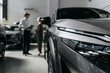 © wedmoments.stock - New car displayed in a showroom while a salesperson consults a buyer in the background. Concept dealership services and vehicle purchase.