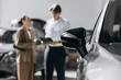 © wedmoments.stock - Modern vehicle displayed prominently in a dealership while customers consider their purchase. Concept car sales and customer service.