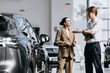 © wedmoments.stock - Female customer discussing the purchase of a new car with a dealership representative.