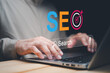© panya7 - SEO search engine optimization concept with business professional using laptop, digital search bar and target icon, representing website ranking, online marketing, traffic and strategy.
