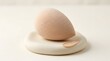 © Aabirah Graphics - Close-up of teardrop-shaped beige cosmetic powder compact on white base for beauty product photography