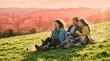 © Ekaterina - Young people enjoying a sunset while sitting on a grassy hill