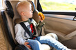 © Olga Murzaeva/Stocksy - A boy with Down syndrome issitting in a car seat in the car