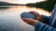 © Milkyway - Person holding a smooth stone by a lake at sunset for wellness and peace