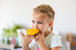 © Austockphoto - Little Australian girl eating a freshly cut mango fruit in kitchen at home