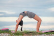 © ADD PHOTO - Yoga woman bridge pose backbend fitness stretch outdoor mat on lakeside grass at sunrise, flexible female athlete practicing training routine, calm focus, healthy lifestyle concept