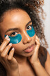 © Gonzalo Infiesta - Young woman applying under eye patches for skincare
