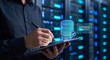 © Thimira - database administrator writes on tablet beside glowing database monitoring interface to confirm database healthy, verify query performance, and manage backup schedule