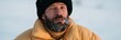 © Andrii Zastrozhnov - Closeup portrait of a bearded man in a winter coat smoking outdoors for editorial background and banner use in cold weather storytelling