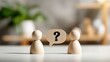 © Zarana  - Wooden figures stand facing each other with a question mark speech bubble between them. This displays a concept for business communication or problem solving.