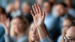 © The Little Hut - Close-up of a hand raised in a crowd of people during a presentation or meeting