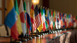 © Pixels by Nazrul - Row of small international flags lined up on a conference table under warm indoor lighting. Ideal for global summits and diplomatic relations concepts.