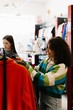 © dsheremeta - Young woman choosing clothes in fashion retail store